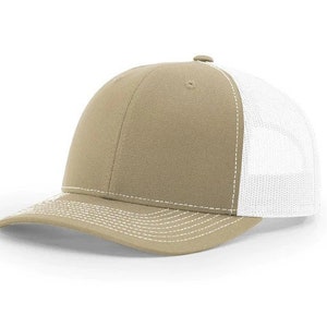 May include: A khaki trucker hat with a white mesh back. The hat has a white stitching detail around the brim and crown.