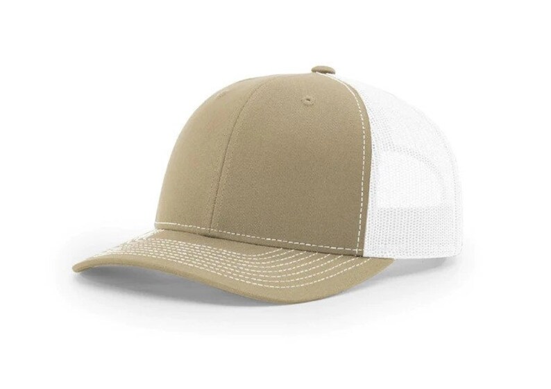 May include: A khaki trucker hat with a white mesh back. The hat has a white stitching detail around the brim and crown.