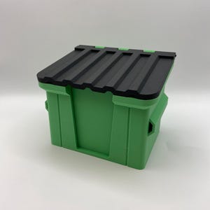 May include: A rectangular storage bin featuring a bright green plastic base with vertical structural ribs and a removable black plastic lid. The lid has a series of parallel ridges across its surface, and the bin includes integrated side handles.