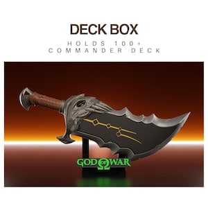 Puede incluir: Una caja para barajas negra con forma de hoja curva, mango marrón y detalles metálicos plateados en la empuñadura. La hoja tiene líneas doradas y el texto "GOD OF WAR" en verde. La caja tiene capacidad para más de 100 cartas de juego.