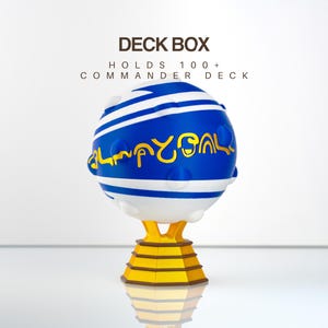 May include: A spherical blue and white deck box with a gold stand, featuring the text DECK BOX HOLDS 100+ COMMANDER DECK. The sphere has horizontal stripes, raised circular bumps, and gold stylized lettering across the center of the blue section.