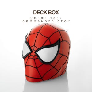Puede incluir: Una caja para barajas roja con un patrón de telaraña negro y ojos blancos grandes, diseñada para contener un mazo de comandante de más de 100 cartas. El texto DECK BOX y HOLDS 100+ COMMANDER DECK aparece sobre el objeto en color marrón.