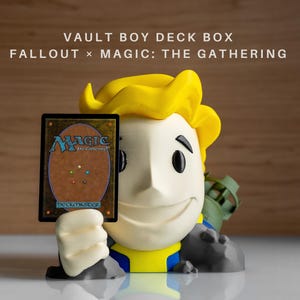 Op de afbeelding: Een Vault Boy deckbox voor Magic: The Gathering kaarten. De doos is ontworpen om op Vault Boy te lijken, met een gele kop en blauwe en gele kleding. De doos bevat een Magic-kaart.