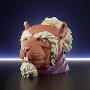 May include: A detailed sculpture of a rodent-like creature's head, featuring a brown face, pink nose, and large white teeth. It has white hair and a purple scarf. The sculpture is set against a dark blue background.