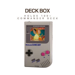 Puede incluir: Una caja para barajas de color gris claro con forma de consola portátil vintage. El texto DECK BOX HOLDS 100+ COMMANDER DECK aparece arriba. El frente muestra una pantalla con una carta de Charizard, una cruceta negra, dos botones rosas y botones SELECT y START azules.