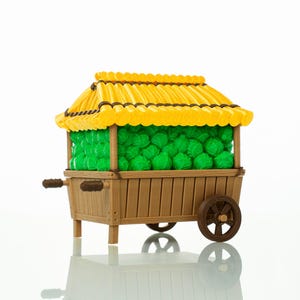 Könnte beinhalten: Ein Miniatur-Marktwagen aus Holz mit gelbem Dach und braunen Akzenten. Der Wagen ist mit grünen Kugeln gefüllt, die möglicherweise Produkte darstellen. Der Wagen hat Räder und Griffe, was darauf hindeutet, dass er mobil ist.