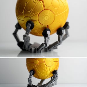 a 3D printed golden sphere with intricate designs, mounted on a robotic arm.