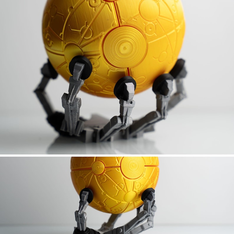a 3D printed golden sphere with intricate designs, mounted on a robotic arm.