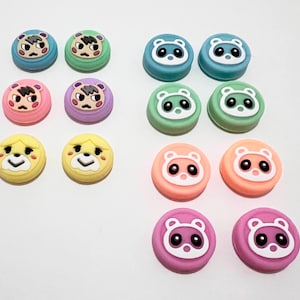 May include: Set of 12 colourful animal face Nintendo Switch controller thumb grips. The grips feature a variety of animal faces, including a raccoon, a squirrel, and a dog. The grips are made of soft silicone and are designed to improve grip and comfort.