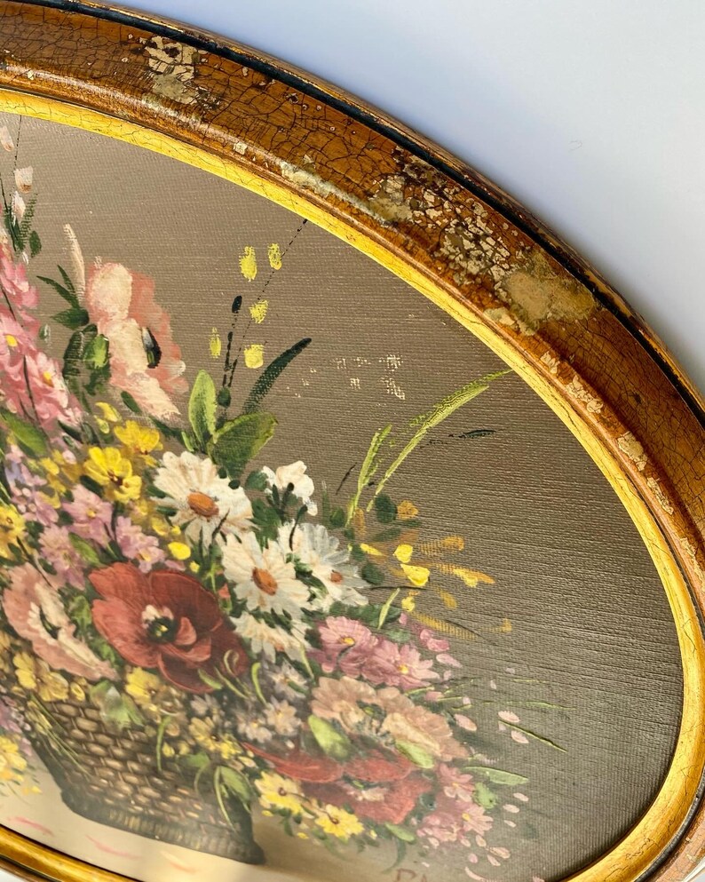 Pu&ograve; includere: Un dipinto ovale vintage incorniciato di un bouquet di fiori colorati in un cesto intrecciato. I fiori sono dipinti in tonalit&agrave; di rosa, rosso, bianco, giallo e verde. La cornice &egrave; di colore oro invecchiato.