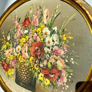 Pu&ograve; includere: Un dipinto incorniciato di un mazzo di fiori colorati in un cesto intrecciato. I fiori includono papaveri rossi, margherite bianche, fiori selvatici rosa e gialli. Il dipinto &egrave; firmato "P.A.V." nell'angolo in basso a destra.