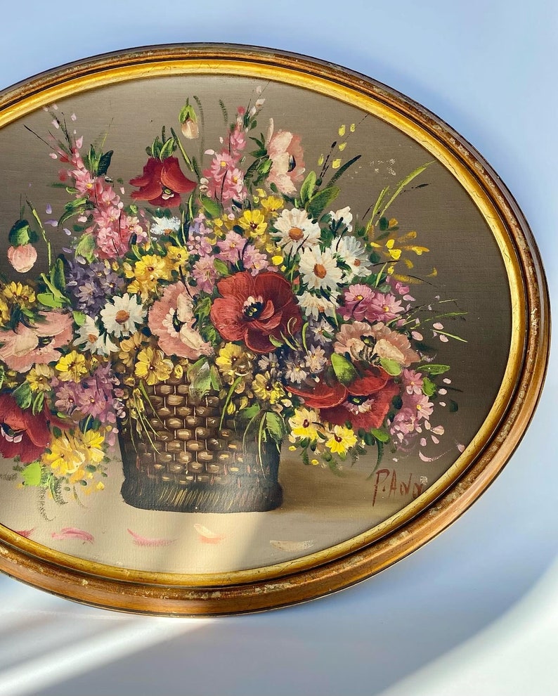 Pu&ograve; includere: Un dipinto incorniciato di un bouquet di fiori colorati in un cesto intrecciato. I fiori sono principalmente rosa, rossi e gialli, e lo sfondo &egrave; un marrone smorzato. Il dipinto &egrave; firmato "P.A.W." nell'angolo in basso a destra.