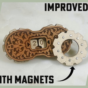 May include: A wooden calendar with a decorative design and a gear-shaped magnet attached. The calendar displays the number "20" and the text "IMPROVED! WITH MAGNETS" is visible below the image.