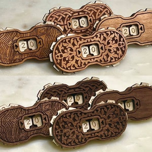 May include: Six wooden counter wheels with a number "20" displayed in a white font. The wheels are in two stacks of three, with each stack featuring a different wood grain pattern. The top stack features a Celtic knot design, a wood grain pattern, and a floral design. The bottom stack features a Celtic knot design, a wood grain pattern, and a floral design.