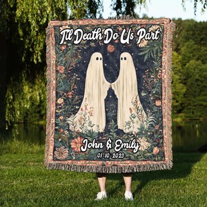 K&ouml;nnte beinhalten: Eine gewebte Wandteppich-Decke mit dunkelblauem Hintergrund, auf der zwei wei&szlig;e Geister Hand in Hand stehen. Der Text "Til Death Do Us Part" ist in wei&szlig;er Kursivschrift oben auf der Decke geschrieben. Der Text "John & Emily 01-10-2023" ist in wei&szlig;er Kursivschrift unten auf der Decke geschrieben.
