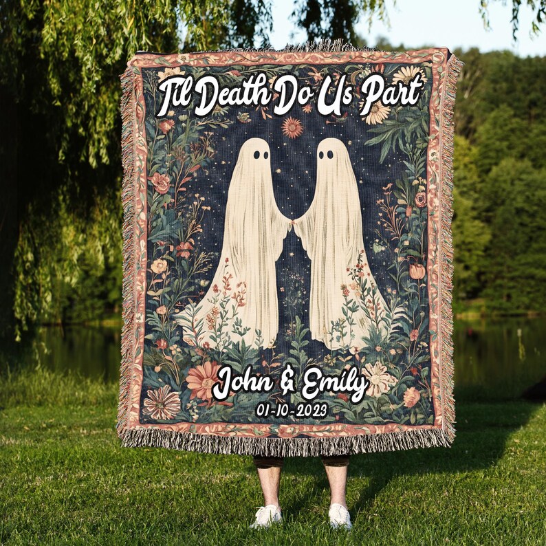 K&ouml;nnte beinhalten: Eine gewebte Wandteppich-Decke mit dunkelblauem Hintergrund, auf der zwei wei&szlig;e Geister Hand in Hand stehen. Der Text "Til Death Do Us Part" ist in wei&szlig;er Kursivschrift oben auf der Decke geschrieben. Der Text "John & Emily 01-10-2023" ist in wei&szlig;er Kursivschrift unten auf der Decke geschrieben.
