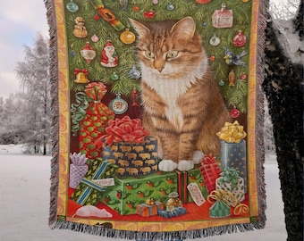 May include: A woven Christmas throw blanket featuring a tabby cat surrounded by wrapped gifts and ornaments. The blanket has a green background with a red border and fringe. The cat is brown and white.