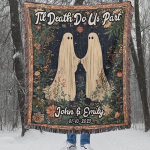 K&ouml;nnte beinhalten: Eine gewebte Wandteppich-Decke mit dunkelblauem Hintergrund, auf der zwei wei&szlig;e Geister zu sehen sind, die sich in einem Blumenfeld die H&auml;nde halten. Der Text "Til Death Do Us Part" befindet sich oben auf der Decke und die Namen "John & Emily" sowie das Datum "01-10-2023" unten.
