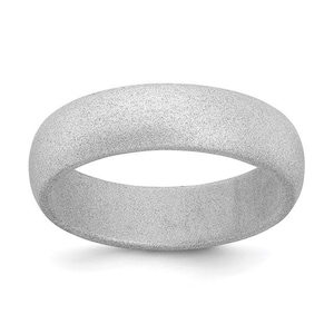 May include: A silver-colored ring with a textured, speckled surface. The ring has a rounded, smooth band. The ring is a simple, elegant piece of jewelry.