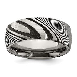 May include: A silver-toned ring with a unique pattern of black and white diagonal lines. The ring has a wide band and a polished interior, creating a striking contrast between the textured exterior and the smooth inner surface.