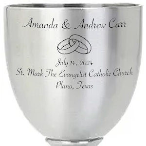 May include: Silver goblet with an engraved inscription: "Amanda & Andrew Carr, July 14, 2024, St. Mark The Evangelist Catholic Church, Plano, Texas". The inscription includes two interlocking rings.