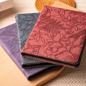 May include: Three different patterned book covers. The top cover is red with a floral design. The middle cover is dark blue with a floral design. The bottom cover is purple with a floral design.