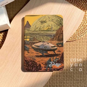 Pode incluir: Uma capa de caderno com uma ilustração colorida de uma paisagem futurista com uma nave espacial e uma pessoa com um traje espacial. O texto "Daisy" está escrito na capa.