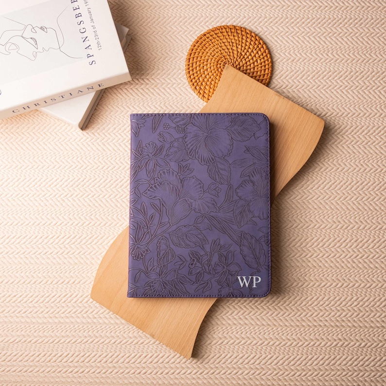 May include: A purple leather notebook with a floral design and the initials "WP" embossed on the front.