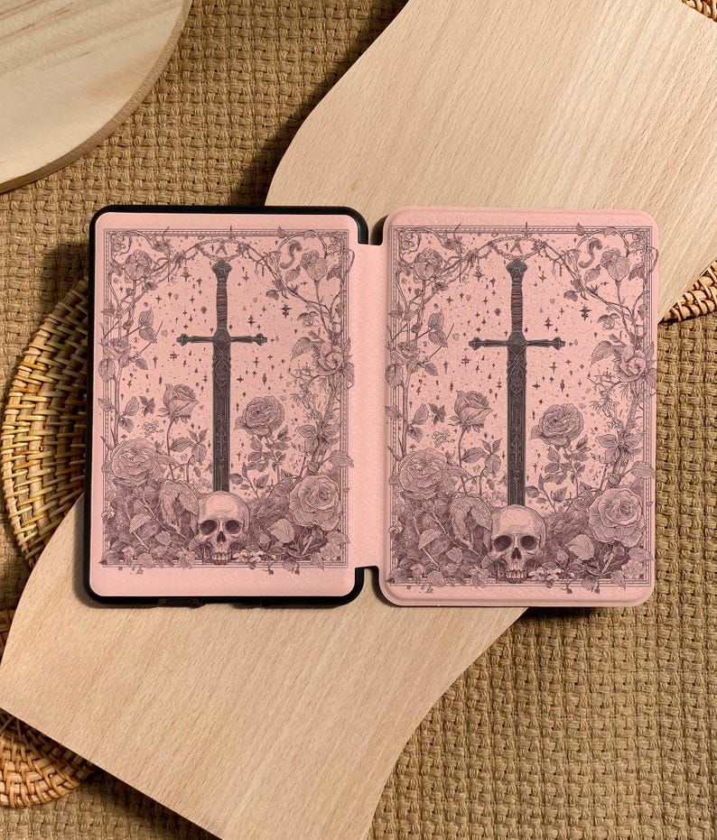 Peut inclure: Un &eacute;tui rose pour liseuse &eacute;lectronique avec un design gothique. L'&eacute;tui pr&eacute;sente une &eacute;p&eacute;e noire, des roses, des cr&acirc;nes et des vignes. Le design est sur fond rose. L'&eacute;tui est ouvert, r&eacute;v&eacute;lant l'int&eacute;rieur.