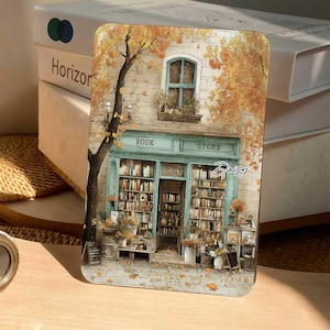 Pode incluir: Uma placa metálica retangular com a ilustração de uma livraria de fachada azul-petróleo, prateleiras cheias de livros e árvores de outono com folhas cor de laranja. O texto "BOOK STORE" está impresso sobre a entrada, com o nome "Daisy".