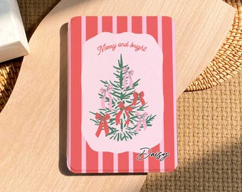 May include: A rectangular, pink and red striped case with a Christmas tree illustration. The tree is decorated with pink bows and red bows. The text "Merry and bright" and "Daisy" are also on the case.