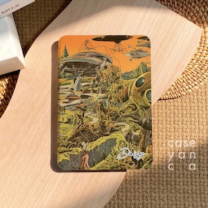 Può includere: Una custodia per telefono colorata con un'illustrazione retrò di fantascienza di dischi volanti, creature strane e un paesaggio. La custodia ha il nome "Daisy" scritto su di essa.