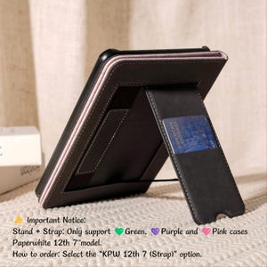 May include: A black leather tablet case with a pink border and a built-in stand. The case has a card slot with an American Express card. The text on the case says "Paperwhite 12th 7" model".