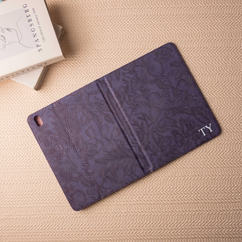 May include: Purple floral patterned iPad case with the initials "TY" embossed in white on the back.
