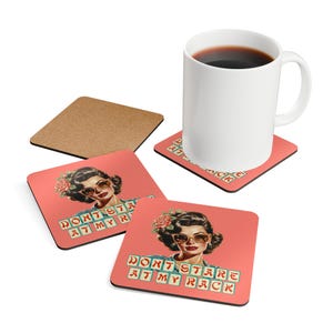 May include: A white ceramic mug filled with coffee sits on a red square coaster. The coaster features a retro illustration of a woman wearing sunglasses and the text "DON'T STARE AT MY RACK". Additional coasters and a cork coaster are also visible.