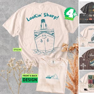 May include: A light beige t-shirt featuring a blue line-art graphic of a ship with a smiling face and the text Lookin' Sharp! on the back, and a smaller ship graphic on the front. The image also displays four additional t-shirt style variations.