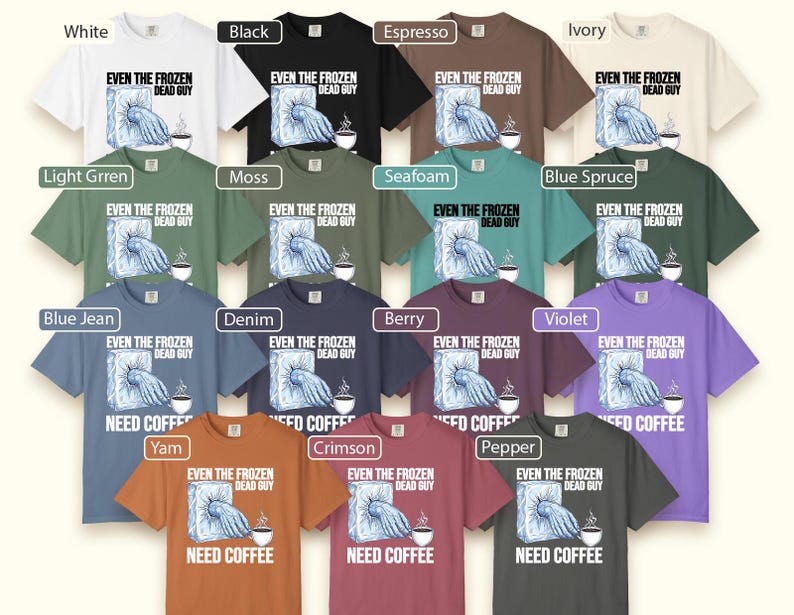 May include: A collection of t-shirts in various colors, including white, black, and blue. Each shirt features the text "EVEN THE FROZEN DEAD GUY" and "NEED COFFEE" with a graphic of a hand emerging from ice and a coffee cup. The shirts are short-sleeved.