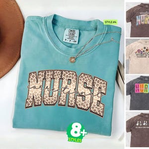 May include: A teal short-sleeved t-shirt with the word NURSE in a leopard print pattern and the word correctional in cursive script. The shirt features a Comfort Colors label and is displayed alongside four other t-shirt style options.