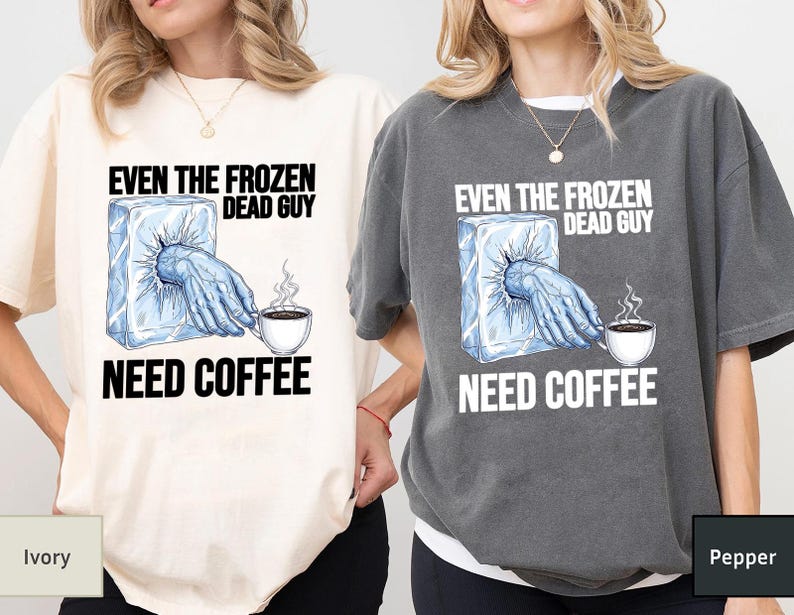 May include: Ivory and pepper-colored t-shirts with the text "EVEN THE FROZEN DEAD GUY NEED COFFEE". The graphic shows a hand reaching out of an ice block, holding a coffee cup.