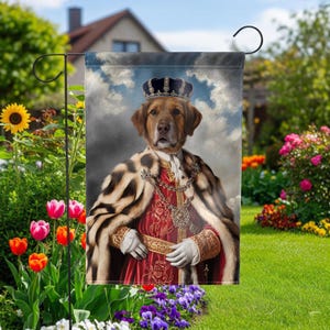 May include: A rectangular garden flag featuring a portrait of a brown dog wearing a royal crown, a red velvet tunic with gold embroidery, and a fur-trimmed cape. The dog is depicted against a cloudy sky background, displayed on a metal stand.