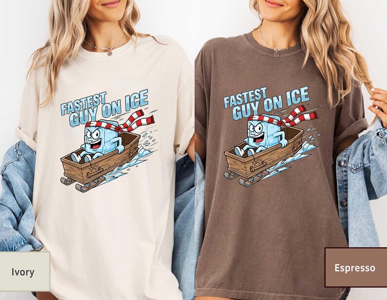 May include: Ivory and espresso-coloured t-shirts with a cartoon ice cube character in a wooden sled. The ice cube wears a red and white striped scarf and the text "FASTEST GUY ON ICE" is above the character.