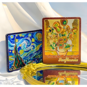 May include: Two square decorative art pieces featuring famous paintings. One depicts Van Gogh's "Starry Night" in blue and yellow. The other showcases "Sunflowers" with gold accents and the artist's name.
