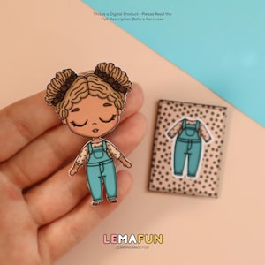 May include: A cartoon doll with brown hair in pigtails wearing a teal jumpsuit and a matching outfit on a small card. The doll is held in a hand. The text "LEMAFUN LEARNING MADE FUN" is at the bottom.