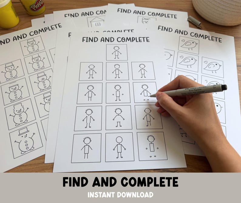 May include: A stack of white printable activity sheets with the text "FIND AND COMPLETE" and illustrations of snowmen, houses, birds, and stick figures. A hand is holding a pen, completing the activity. The words "INSTANT DOWNLOAD" are also visible.
