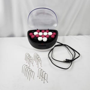 May include: A black and white hair roller set with a clear plastic lid. The set includes a base with pink, white, and black rollers, along with metal clips and a power cord. The rollers are designed for creating curls.
