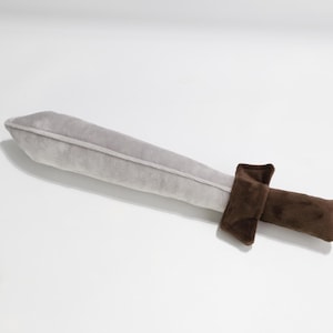 Soft plush sword toy with a light gray blade and brown handle, designed to resemble a medieval or fantasy weapon. Perfect for safe play, costumes, or imaginative battles. Handmade by GraTY Foundation – a Polish social enterprise supporting neurodivergent individuals through creative sewing and inclusive employment.