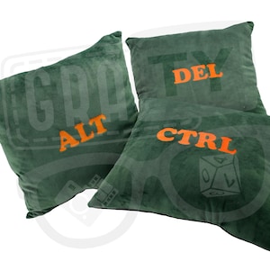 Könnte beinhalten: Drei grüne Dekokissen mit orangefarbenem Sticktext. Die Kissen zeigen "ALT", "CTRL" und "DEL".