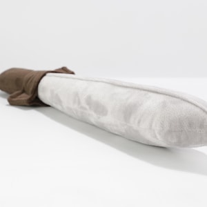 Close-up view of a soft plush toy sword lying on a white surface. The blade is made of light gray velvety fabric, and the hilt is crafted from a rich brown plush. The rounded tip and soft textures make it safe for children. Handmade by the GraTY Foundation—an inclusive social enterprise empowering neurodivergent creators through sewing and imaginative play.