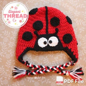 Può includere: Cappello da coccinella a uncinetto rosso e nero con lacci intrecciati bianchi e neri. Il cappello ha un viso nero con occhi bianchi e un naso nero. Il cappello è su uno sfondo con motivo floreale.  File PDF.