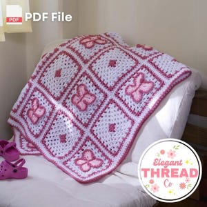 Puede incluir: Una manta de bebé de crochet rosa y blanca con un diseño de mariposa. La manta está doblada y colocada en un sofá blanco. El texto "Elegant Thread Co." es visible en la esquina inferior derecha de la imagen.